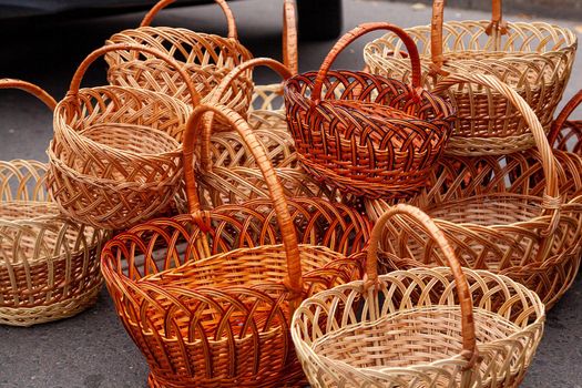 Group of empty wicker baskets for sale in a market place. Heap of wicker baskets dark brown oval round sale at the farmers market
