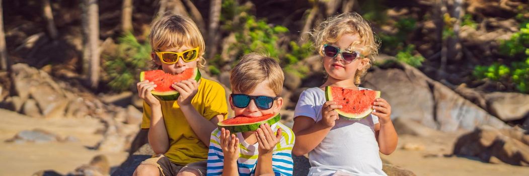 Children eat watermelon on the beach in sunglasses. BANNER, LONG FORMAT