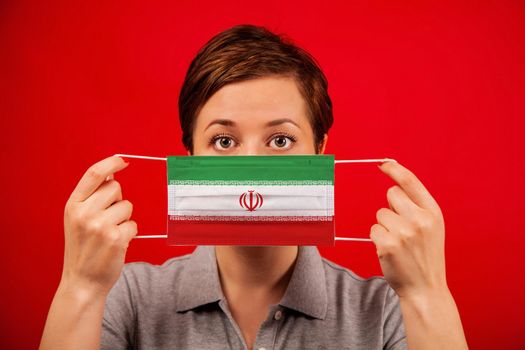 Coronavirus COVID-19 in Iran. Woman in medical protective mask with the image of the flag of Iran. The concept of preventing the spread of the epidemic and treating coronavirus.