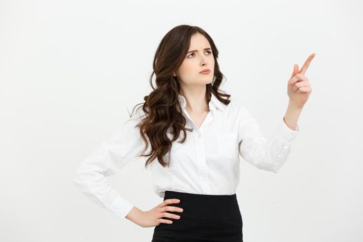 Business Concept: Portrait of surprised young businesswoman pointing finger away to copy space. Isolated on a white background