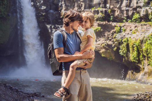 Dad and son tourists on the background of a waterfall. Traveling with kids concept. What to do with children Children friendly place.