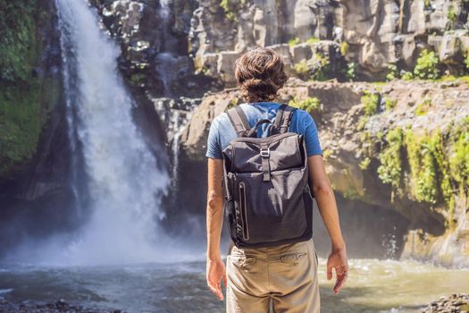 Man traveler on a waterfall background. Ecotourism concept.