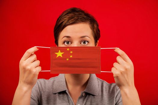 Coronavirus COVID-19 in China. Woman in medical protective mask with the image of the flag of China. The concept of preventing the spread of the epidemic and treating coronavirus.
