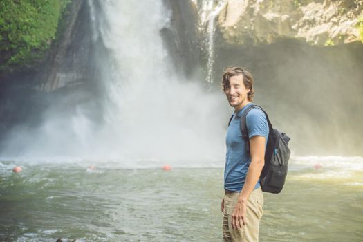 Man traveler on a waterfall background. Ecotourism concept.