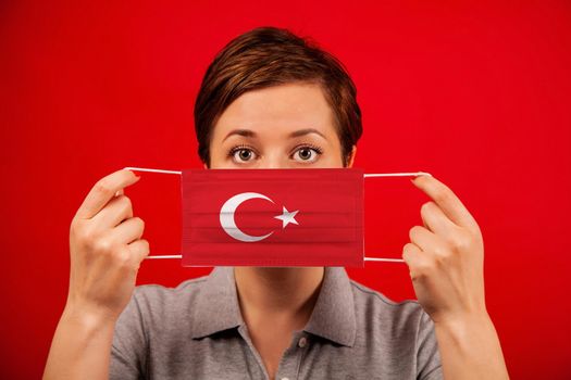Coronavirus COVID-19 in Turkey. Woman in medical protective mask with the image of the flag of Turkey. The concept of preventing the spread of the epidemic and treating coronavirus.