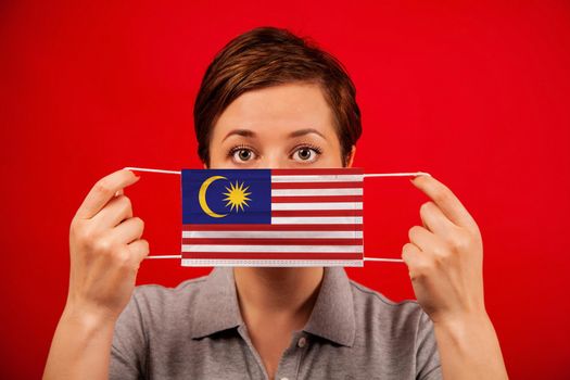 Coronavirus COVID-19 in Malaysia. Woman in medical protective mask with the image of the flag of Malaysia. The concept of preventing the spread of the epidemic and treating coronavirus.