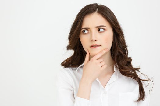 Thinking Caucasian business woman with hand on her chin and looking up on grey backgroud