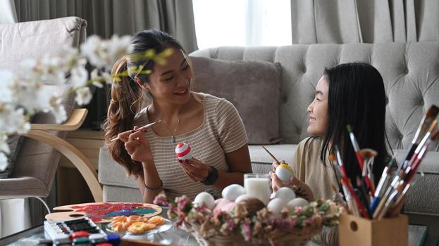 Beautiful asian mother and her daughter celebrating Easter festival, painting eggs together. Easter holidays concept.