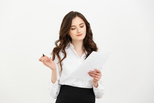 Focused young woman holding sheet of paper and reading. Document concept. Isolated front view on white background