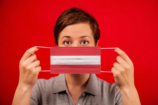 Coronavirus COVID-19 in Austria. Woman in medical protective mask with the image of the flag of Austria. The concept of preventing the spread of the epidemic and treating coronavirus.