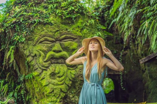 Young woman traveler in a Balinese garden overgrown with moss. Travel to Bali concept.