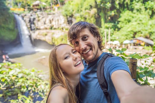 smiling couple, man and woman making selfie on a waterfall background.