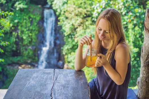 Closeup portrait image of a beautiful woman drinking ice tea with feeling happy in green nature and waterfall garden background.