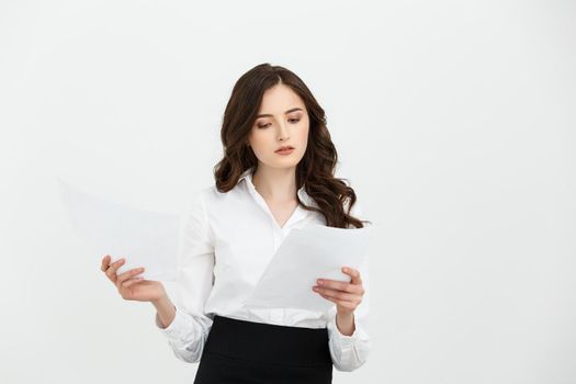 Focused young woman holding sheet of paper and reading. Document concept. Isolated front view on white background