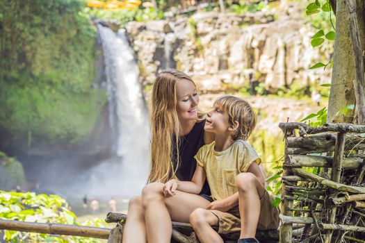 Mom and son tourists on the background of a waterfall. Traveling with kids concept. What to do with children Children friendly place.