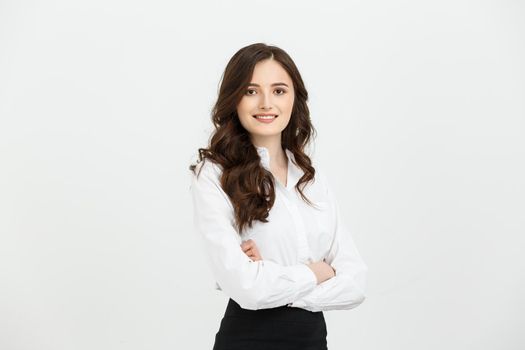 Business Concept: Portrait confident young businesswoman keeping arms crossed and looking at camera while standing against grey background.