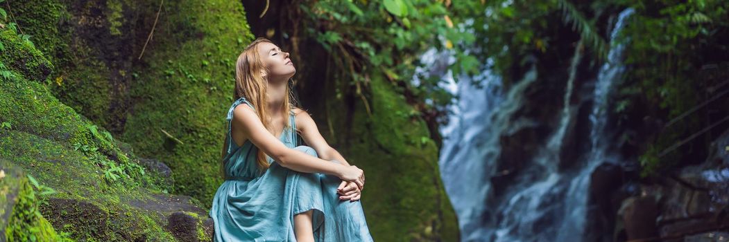 Woman traveler on a waterfall background. Ecotourism concept. BANNER, LONG FORMAT