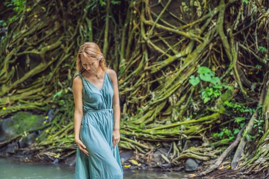 Young woman traveler in a Balinese garden overgrown with moss. Travel to Bali concept.