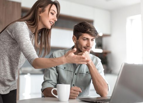 Young couple looking discussing online news in the kitchen. people and technology