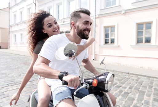 Happy cheerful couple riding vintage scooter outdoors.