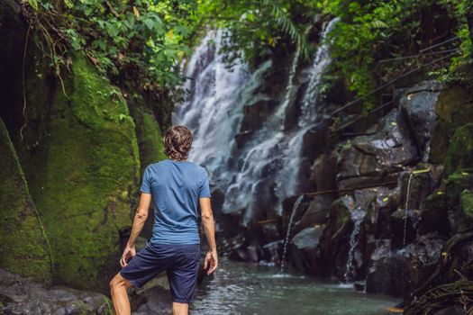 Man traveler on a waterfall background. Ecotourism concept.