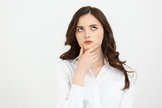 Thinking Caucasian business woman with hand on her chin and looking up on grey backgroud