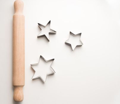 High angle view of rolling pin and cookie cutter stars on white table