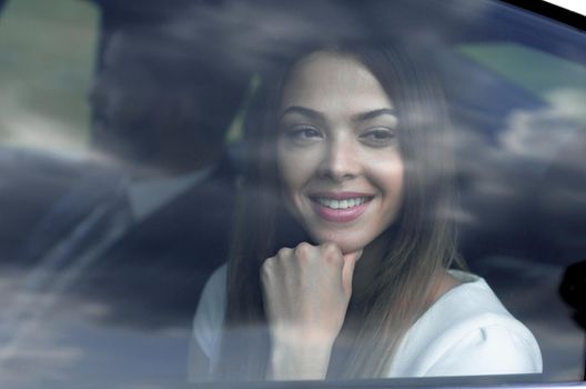 woman sitting in a moving car, looking through her window towards