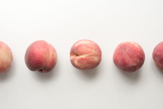 High angle view of five white peaches arranged in a row on table