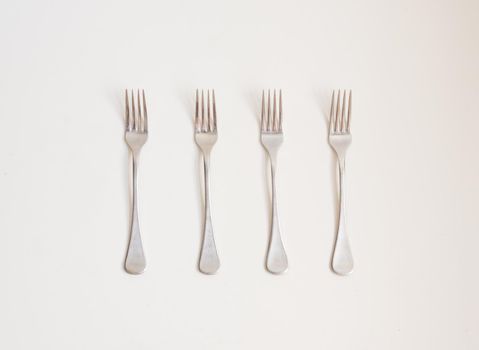 Food background - high angle view of four forks in a row on a white table