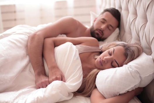 hotel, travel, relationships, and happiness concept - happy couple sleeping in bed