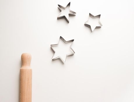 High angle view of rolling pin and cookie cutter stars on white table (cropped)