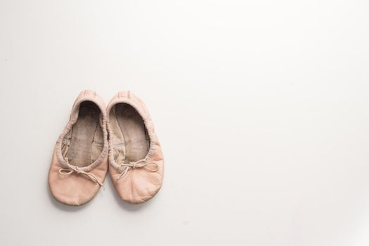 High angle view of old, dirty little girl's pink ballet shoes on white table with copy space to right