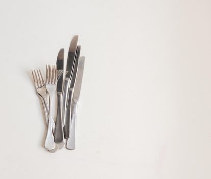 Food background - high angle view of four forks and knives on white table with copy space to right