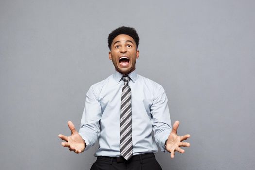 Business Concept - Confident cheerful young African American showing hands in front of him with disappointed expression over grey background