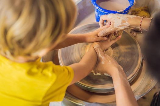 mother and son doing ceramic pot in pottery workshop. What to do with children. Child friendly place.