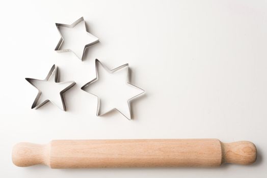 High angle view of rolling pin and cookie cutter stars on white table with copy space to right