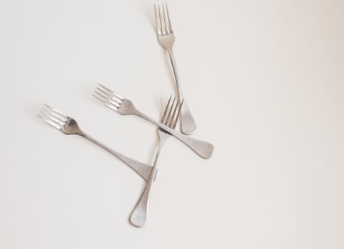 Food background - high angle view of four forks scattered on white table with copy space to right