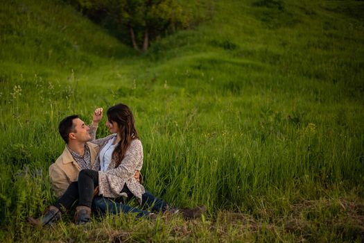 Loving hipster couple walking in the field, kissing and holding hands, hugging, lying in the grass in the summer at sunset. valentines day