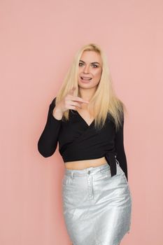 Fashion model woman in fashionable clothes on pink background. Wearing stylish clothing, black blouse, silver skirt. Posing in studio