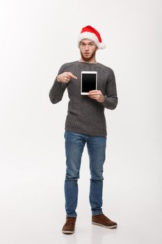 Holiday and Business Concept - Young handsome man showing tablet display and pointing finger presenting.