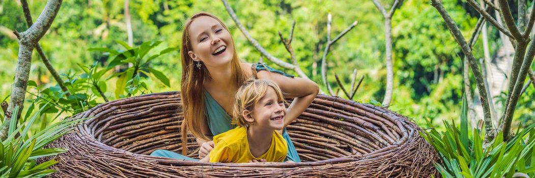 BANNER, LONG FORMAT Bali trend, straw nests everywhere. Happy family enjoying their travel around Bali island, Indonesia. Making a stop on a beautiful hill. Photo in a straw nest, natural environment. Lifestyle. Traveling with kids concept. What to do with children. Child friendly place.