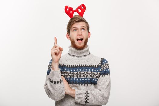 Holiday Concept - Young beard man in sweater enjoy playing and pointing finger upward.