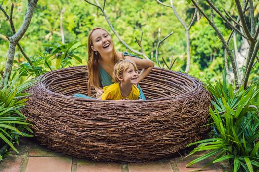 Bali trend, straw nests everywhere. Happy family enjoying their travel around Bali island, Indonesia. Making a stop on a beautiful hill. Photo in a straw nest, natural environment. Lifestyle. Traveling with kids concept. What to do with children. Child friendly place.