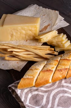 hard cheese and fibrous cheese with slices of bread are cut on a wooden board