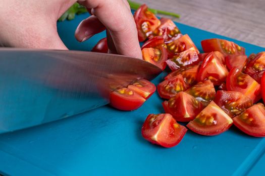 Slicing salad. Girl finely chop red tomatoes with a knife in the kitchen.