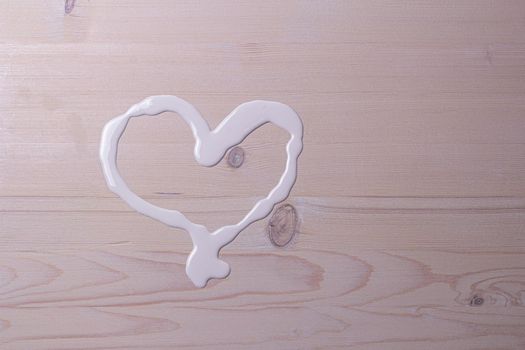 spilled white paint in the shape of a heart on a wooden table
