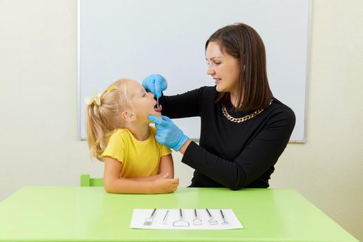 Speech therapist working with little girl in office training correct pronunciation