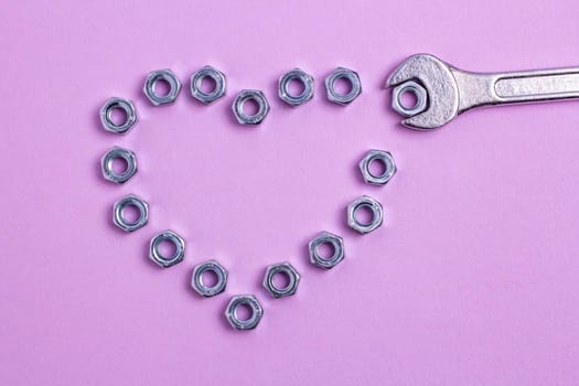 The heart of the nuts with a wrench on a purple paper background. Brutal heart for Valentine's Day