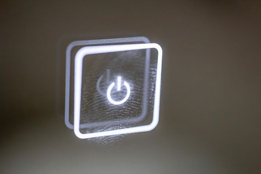 a glowing touch button stained with finger marks. turn on off. copy space